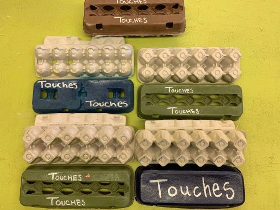 Several touch cartons open to show both top with the “Touches” label and bottoms with the touch words.